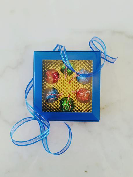 A royal blue box and ribbon with festive coloured foil-wrapped chocolates.