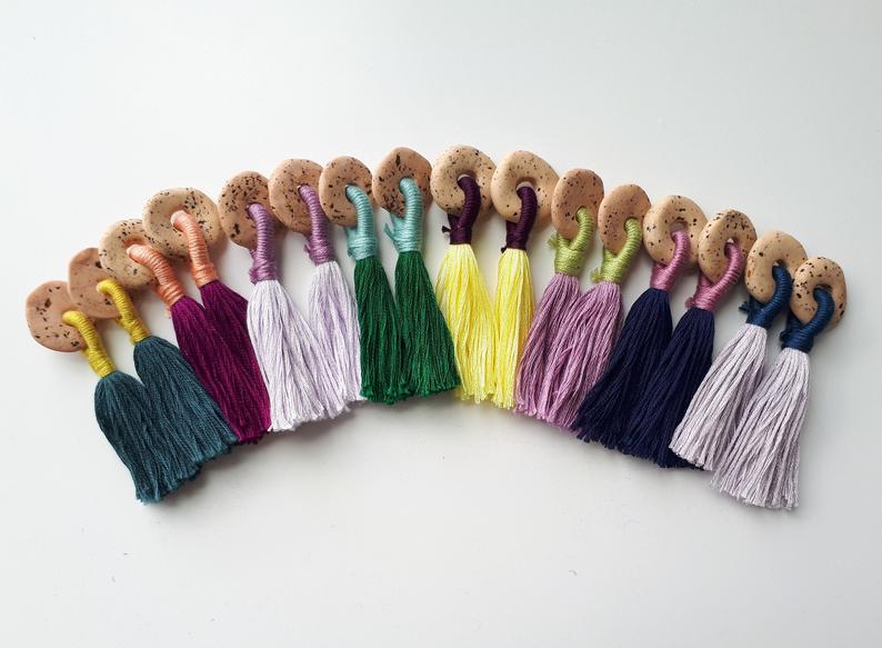 A rainbow assortment of round clay earrings with multi-coloured tassels.