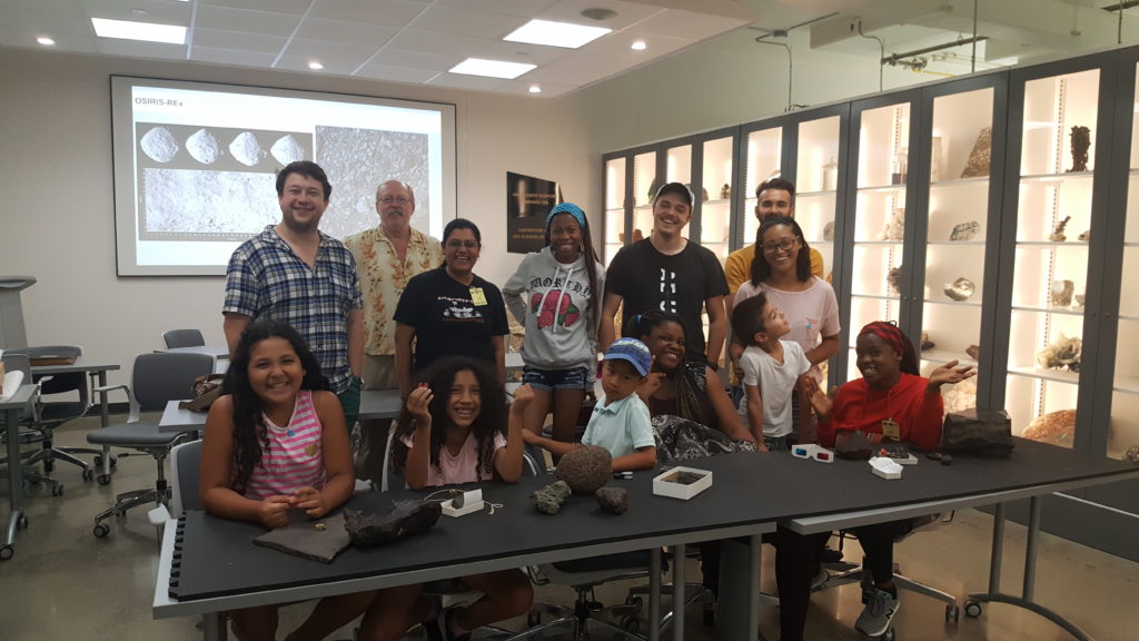 Group of students and staff at Indus space classroom smiling and posing for camera.