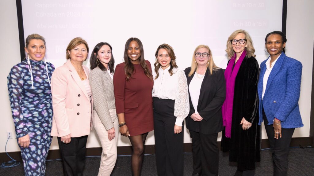 Eight diverse women smiling and posing for the camera at an event.