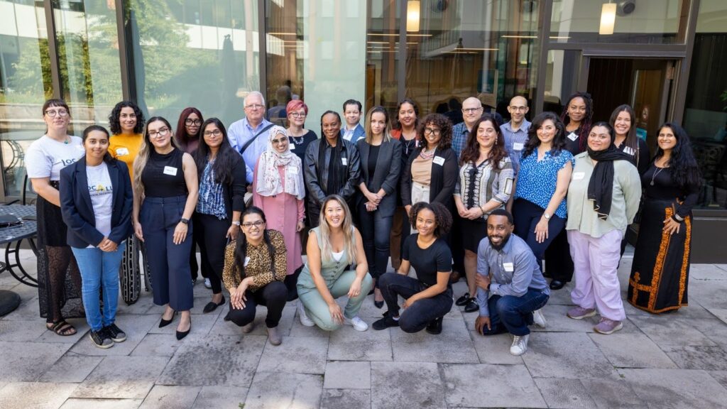 A large group of diverse mentors and entrepreneurs gather together, smiling and posing for a photo.