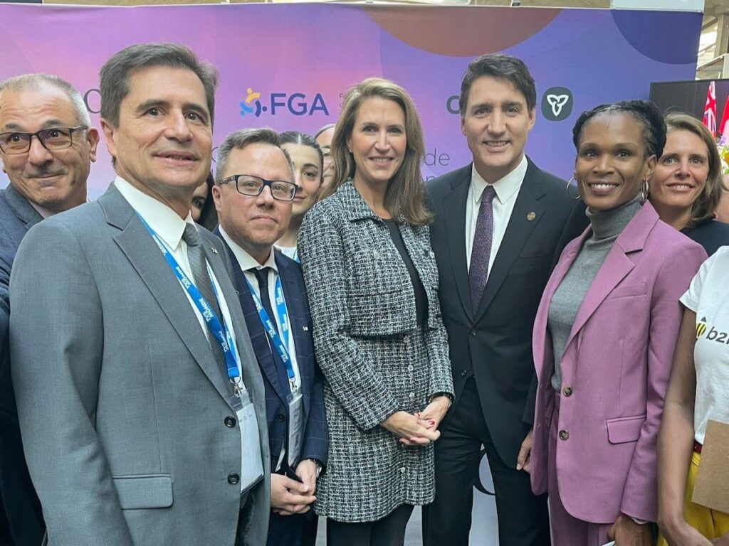 A group of ten people posing for the camera and smiling at a conference.