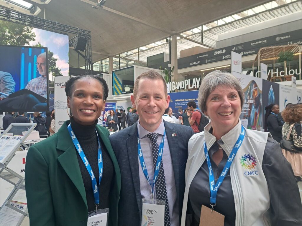 Two women and one man smiling for the camera at a conference.