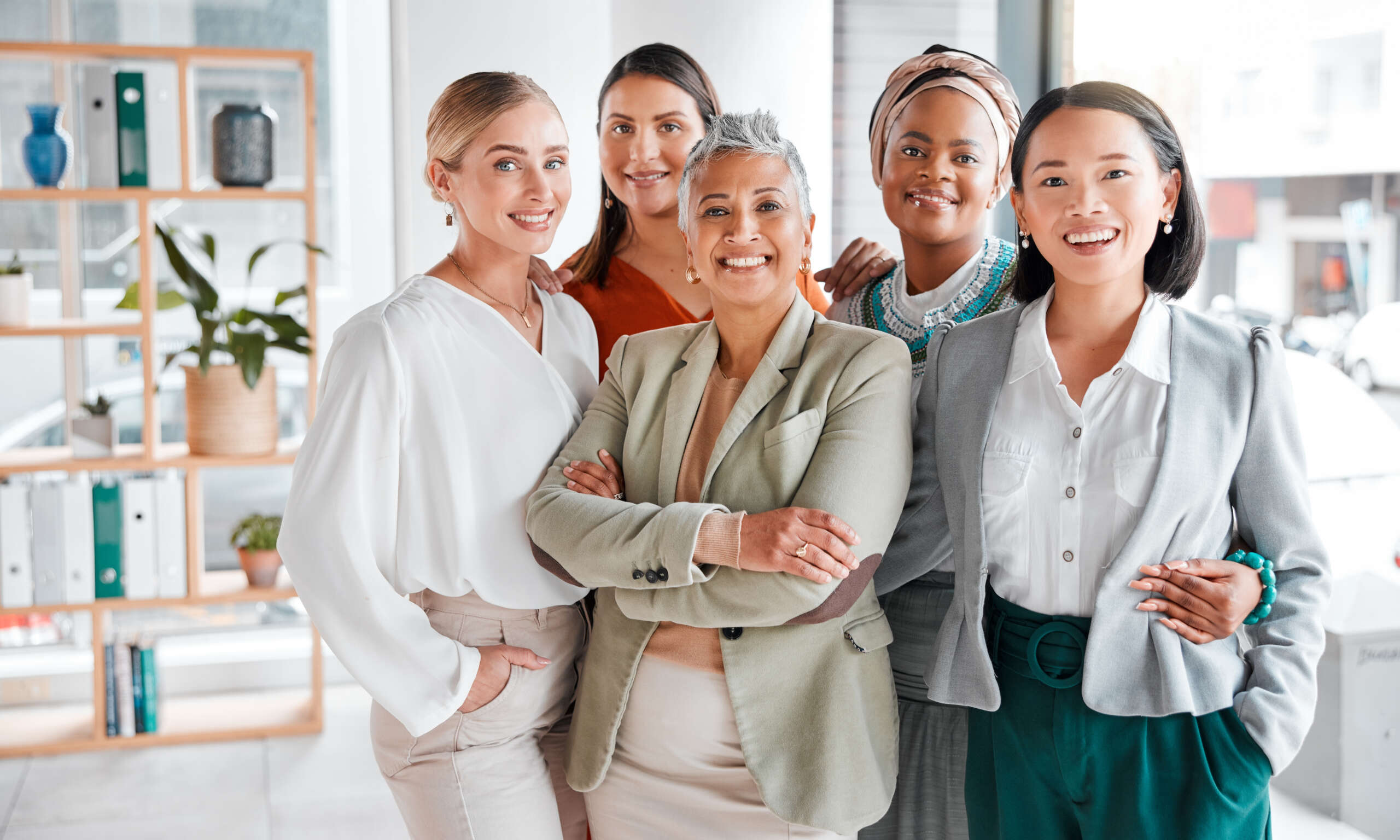 Five diverse business women standing in an office.
